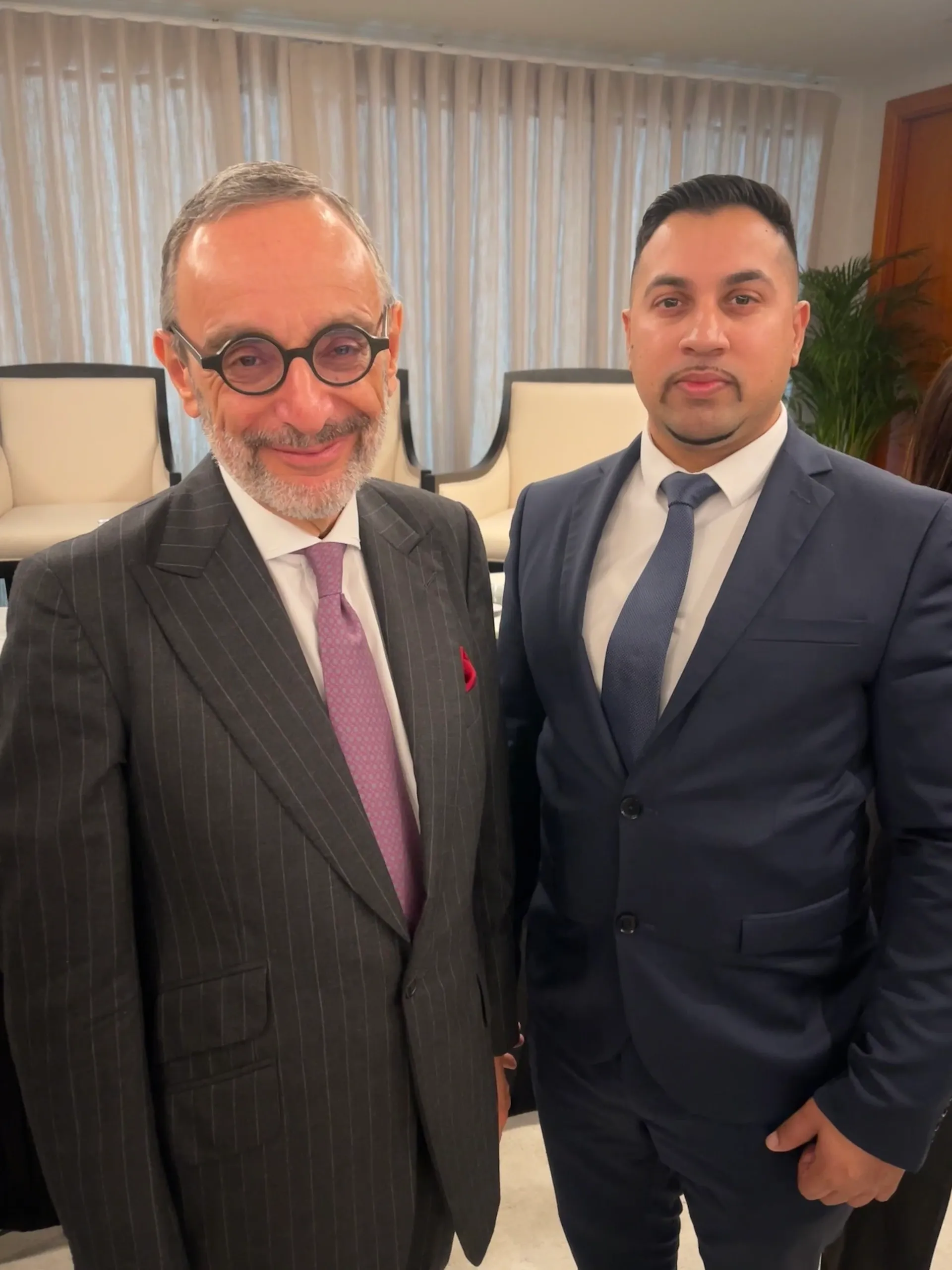 Two men in suits standing together indoors.
